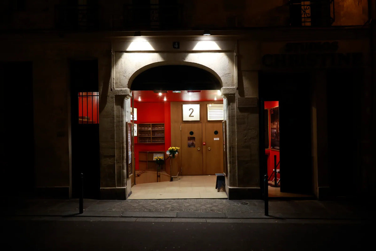 Façade de boutique parisienne illuminée le soir, porche rouge et lampes