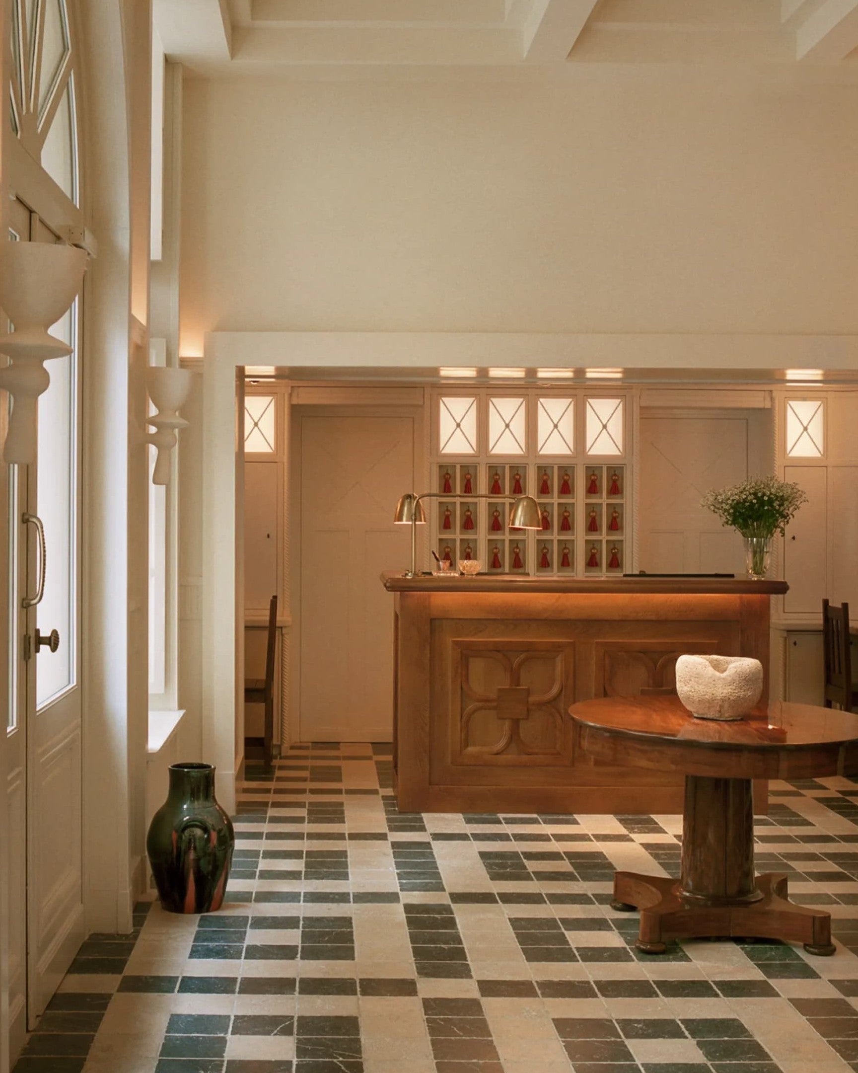 Hall d'entrée élégant avec sol en carrelage à damier et mobilier en bois