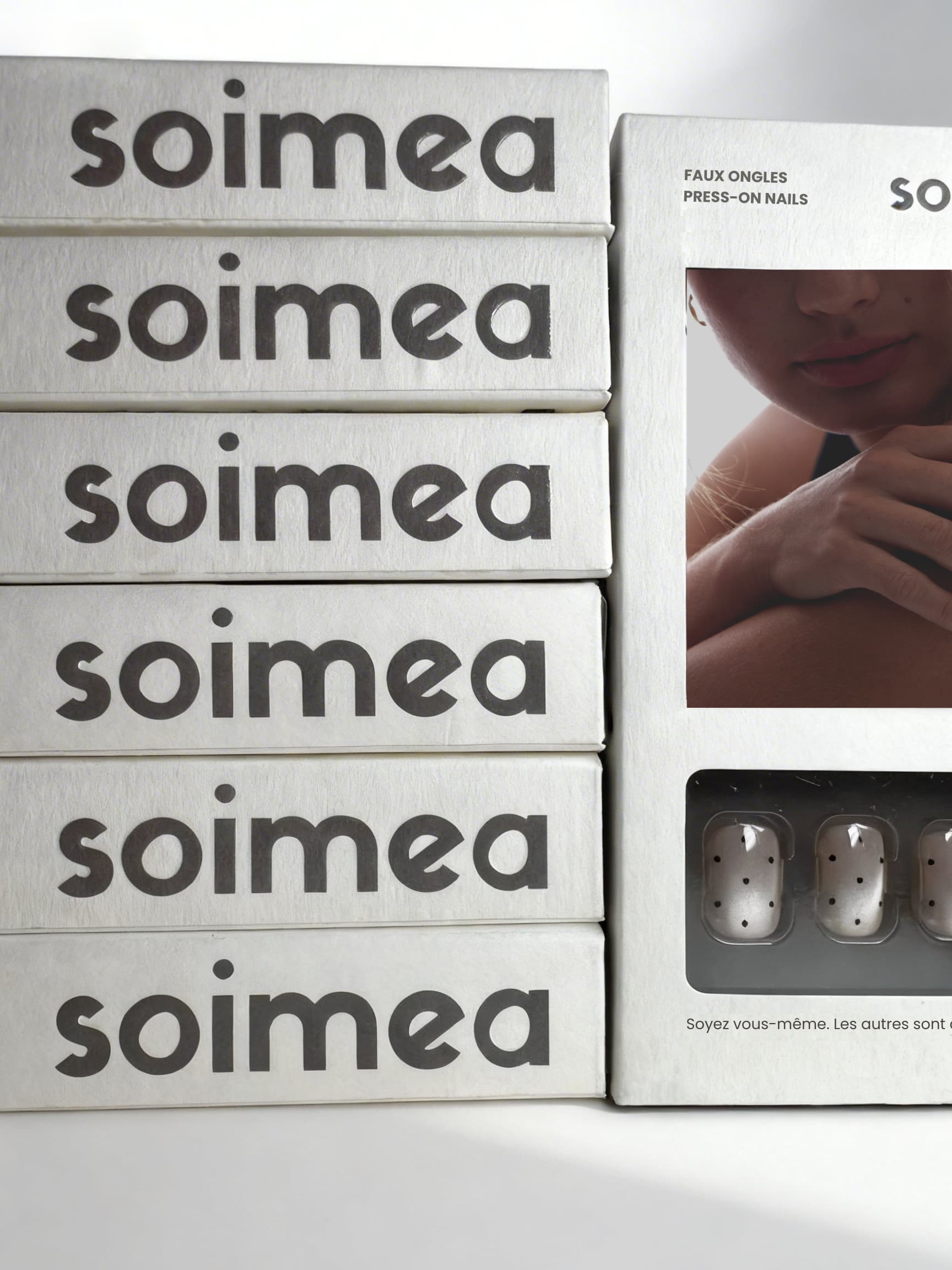 Boîtes de faux ongles press-on Soimea empilées avec packaging et main manucurée