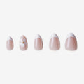 Manucure Eveil Nymphal portée sur la main. Teinte rose, blanc au motif floral. faux ongles press-on en forme amande. Par SOIMEA Paris
