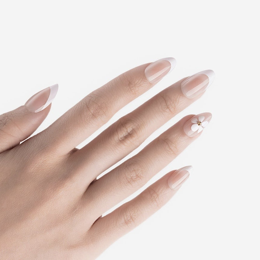 Manucure Eveil Nymphal portée sur la main. Teinte rose, blanc au motif floral. faux ongles press-on en forme amande. Par SOIMEA Paris