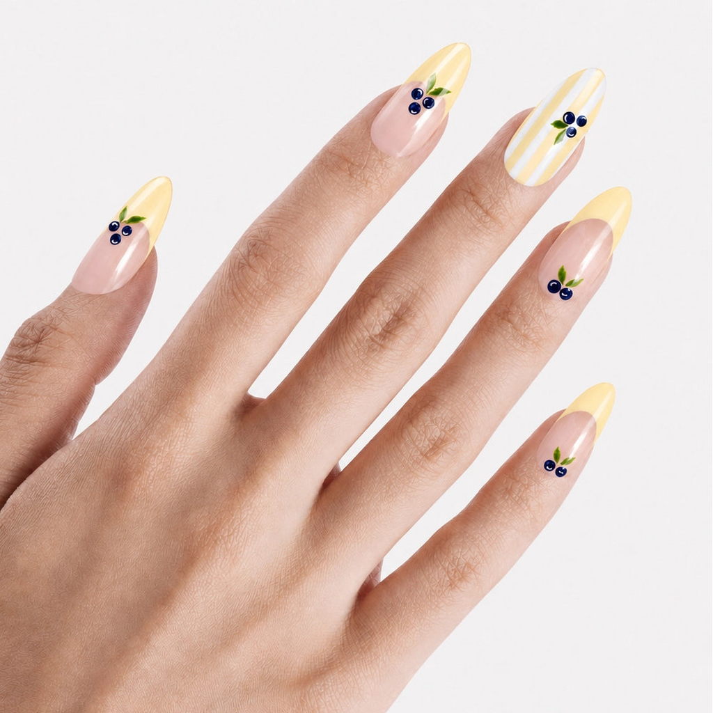 Faux ongles press-on Mirtillo portés sur la main, manucure longue amande nude avec French jaune beurre et myrtilles 3D