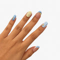 Faux ongles press-on Limoncello courts ronds avec rayures bleu blanc portes sur les mains, citrons jaunes, French festivale et soleil transparent 3D. Par SOIMEA Paris