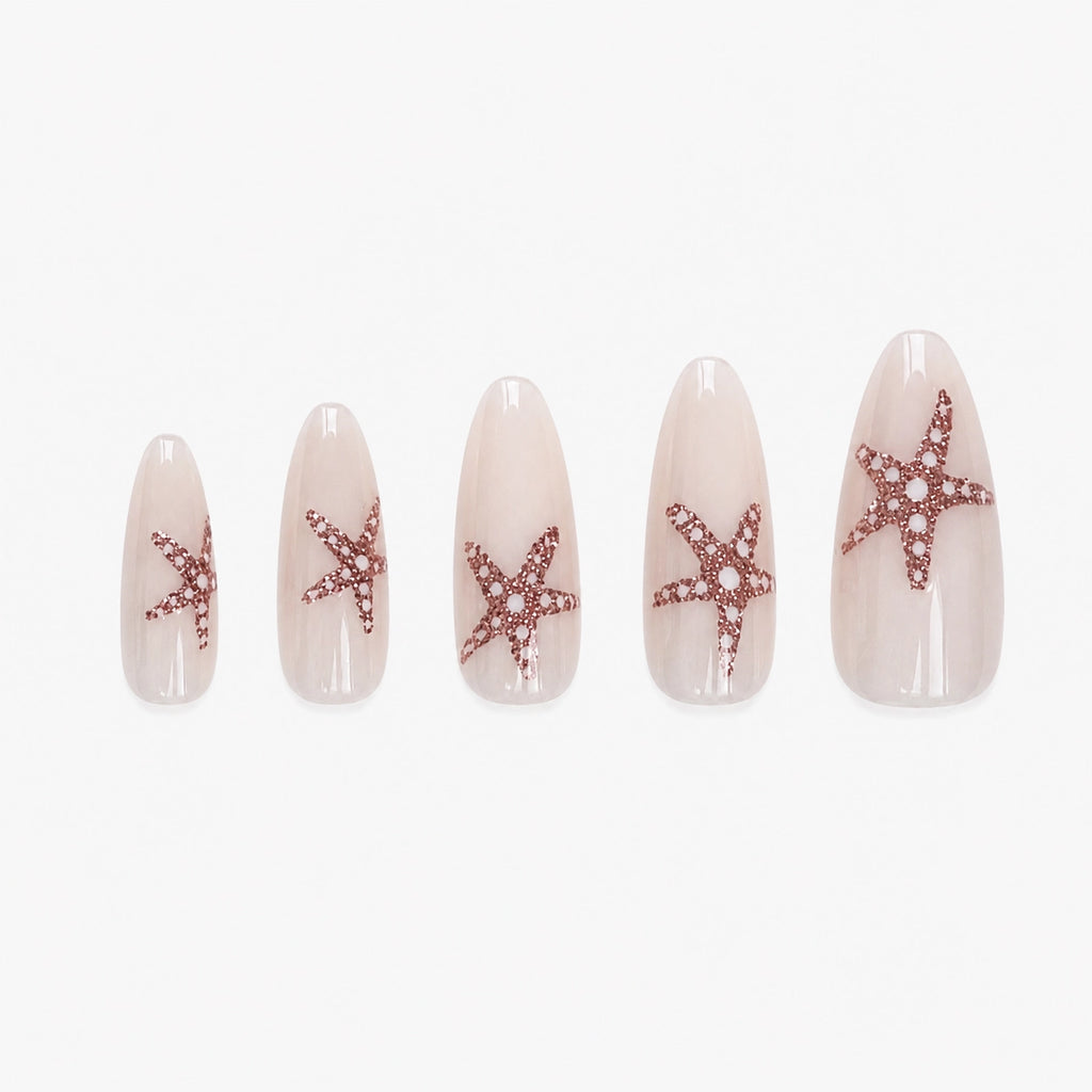 Faux ongles press-on Stella Marina longs amande blanc lacté avec étoiles de mer en paillettes or orangé inspirées de la plage