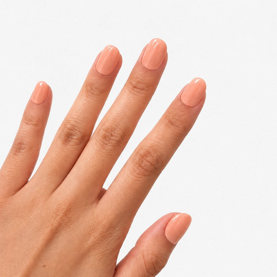 Manucure Nude Abricot portée sur la main, faux ongles press-on courts arrondis nude pêche brillant effet naturel