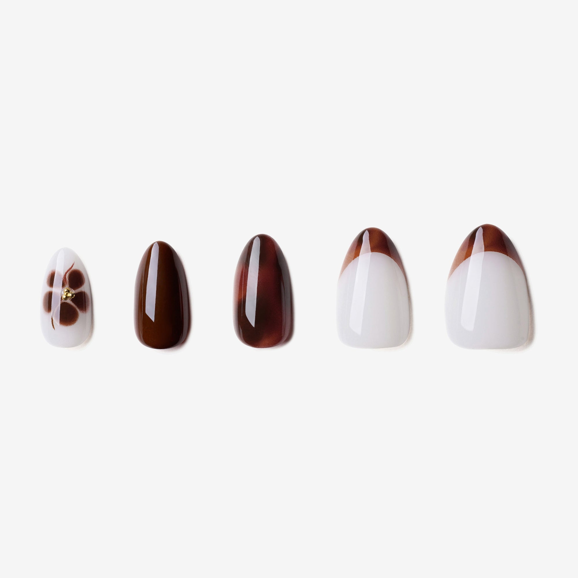 Manucure Petit Féline portée sur la main. Teinte marron, blanc au motif floral. Faux ongles press-on en forma amande. Par SOIMEA Paris