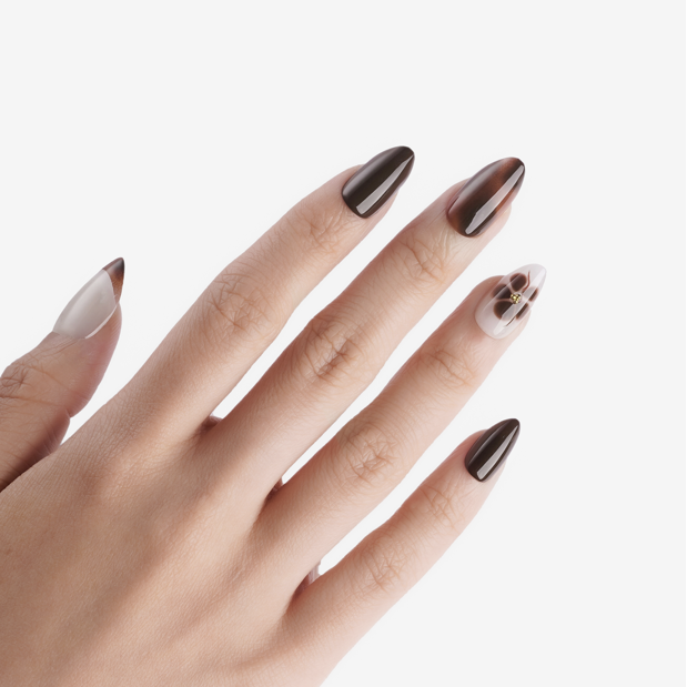 Manucure Petit Féline portée sur la main. Teinte marron, blanc au motif floral. Faux ongles press-on en forma amande. Par SOIMEA Paris