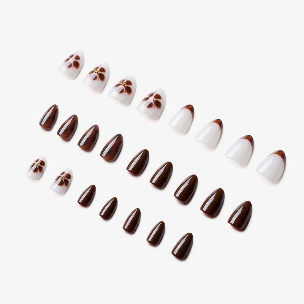 Manucure Petit Féline portée sur la main. Teinte marron, blanc au motif floral. Faux ongles press-on en forma amande. Par SOIMEA Paris