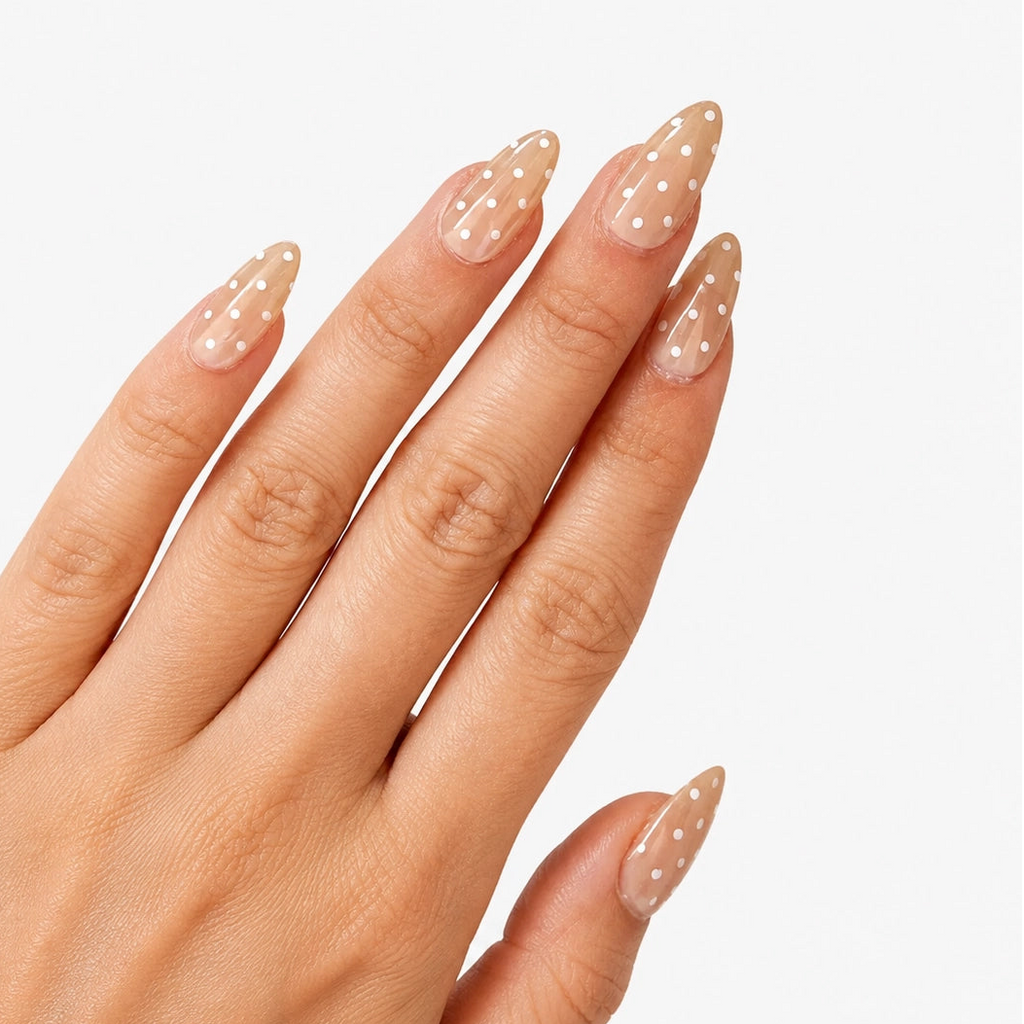 Manucure Chouchette portée sur la main. Teinte beige avec motif à pois blanc. Faux ongles press-on en forme d'amande. Effet brillant naturel. Par SOIMEA Paris